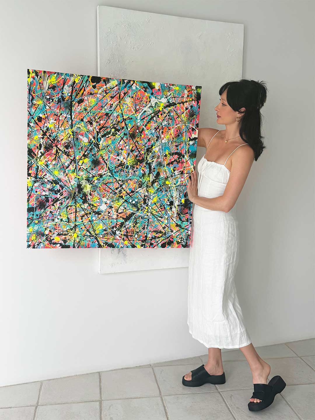 Image of Bridget Bradley, Contemporary Abstract Artist Wearing White Dress, Holds her Original Canvas Painting, 'Labyrinth'