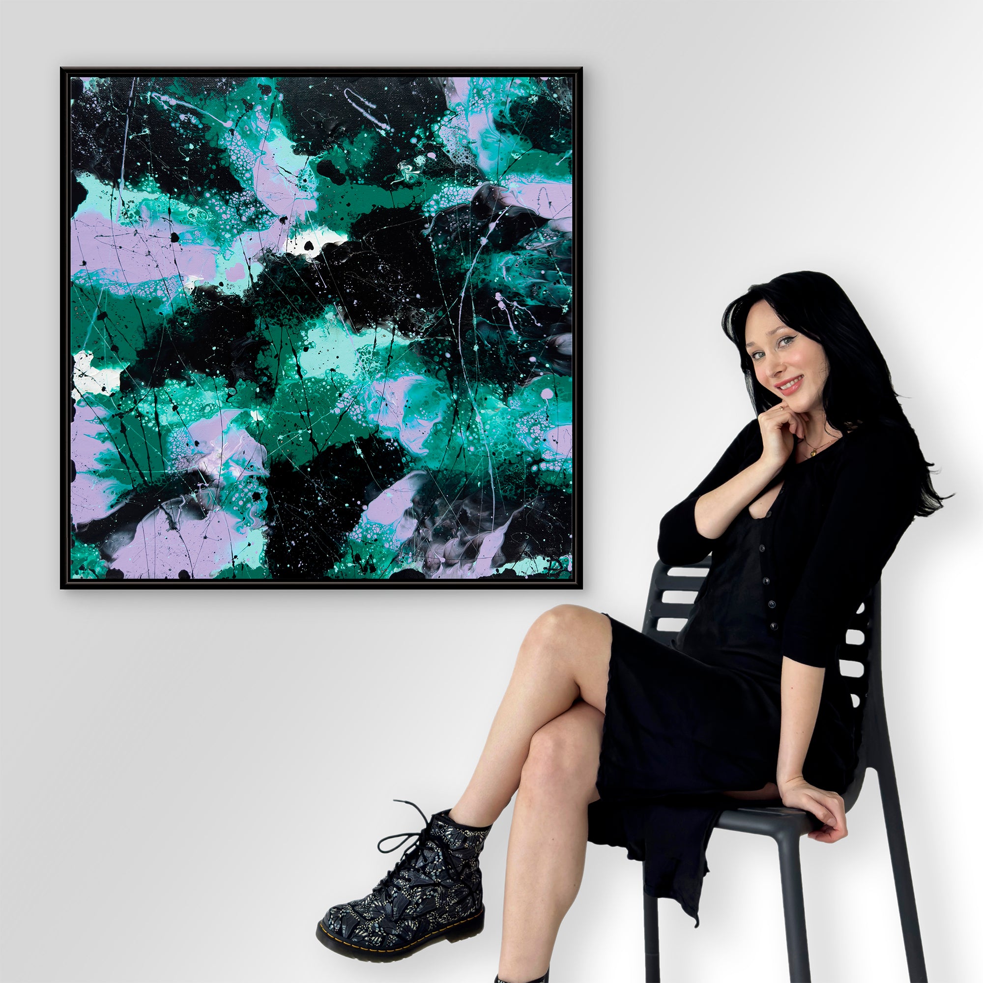 Bridget Bradley contemporary abstract artist sitting on a chair next to a colourful fine art abstract print on a white wall, after her original artwork, 'Forest I '