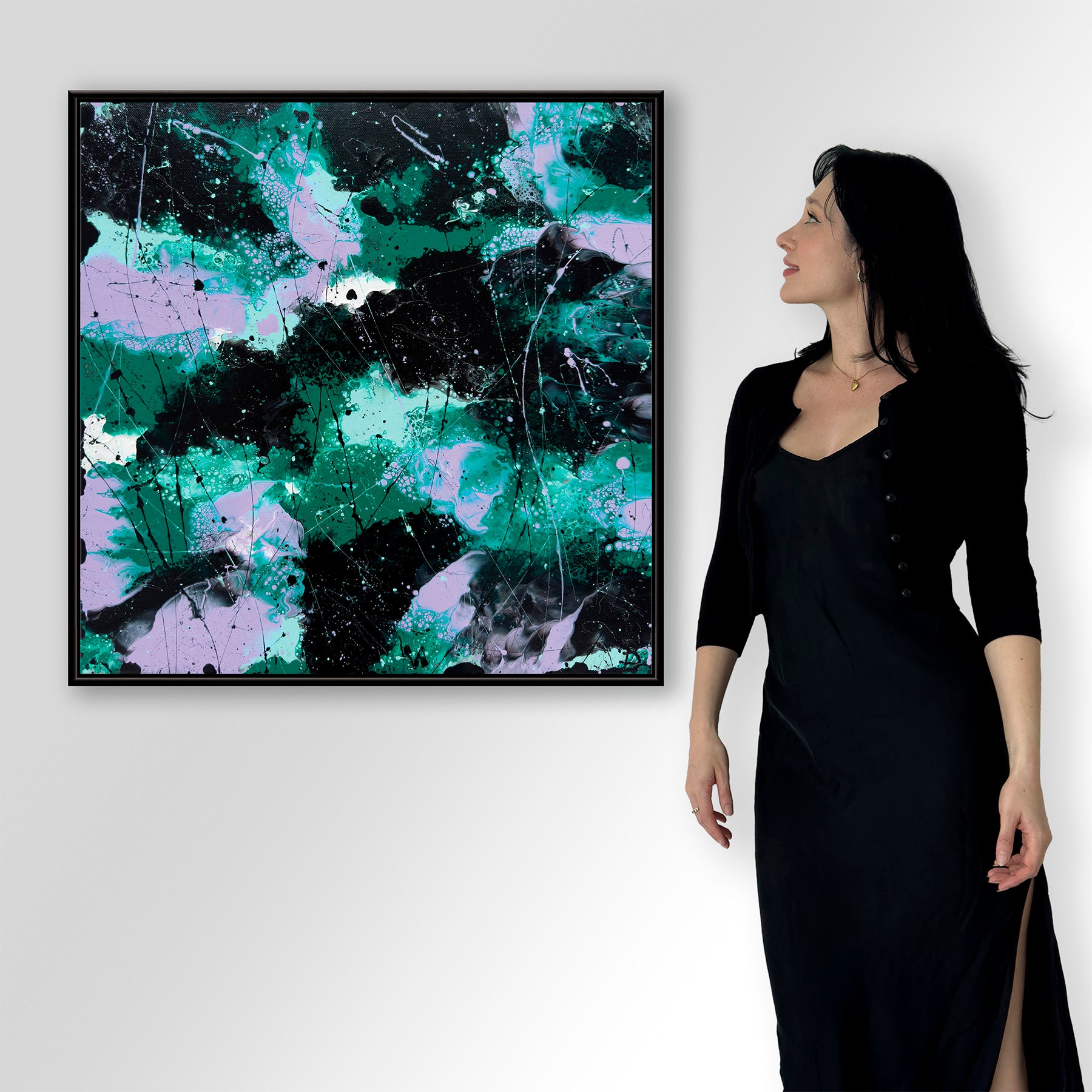 Bridget Bradley, contemporary abstract artist in a black dress standing next to a large abstract fine art print 'Forest I' on a white wall