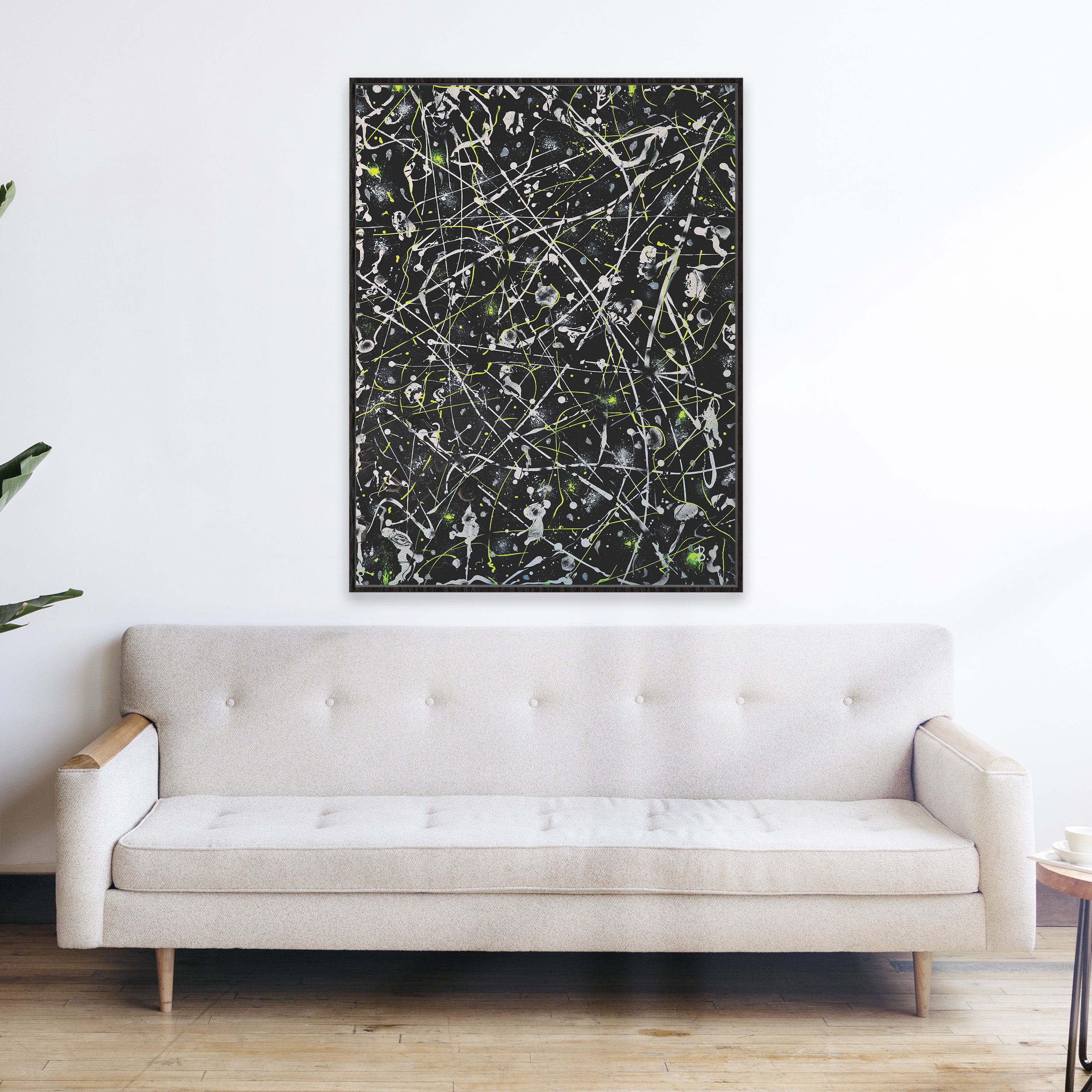 'Space Rock Canvas Print' framed in black seen hanging above a silver grey sofa in situ. Canvas prints at BRIDGET BRADLEY Art are affordable, gig-quality and contemporary art available for worldwide shipping.