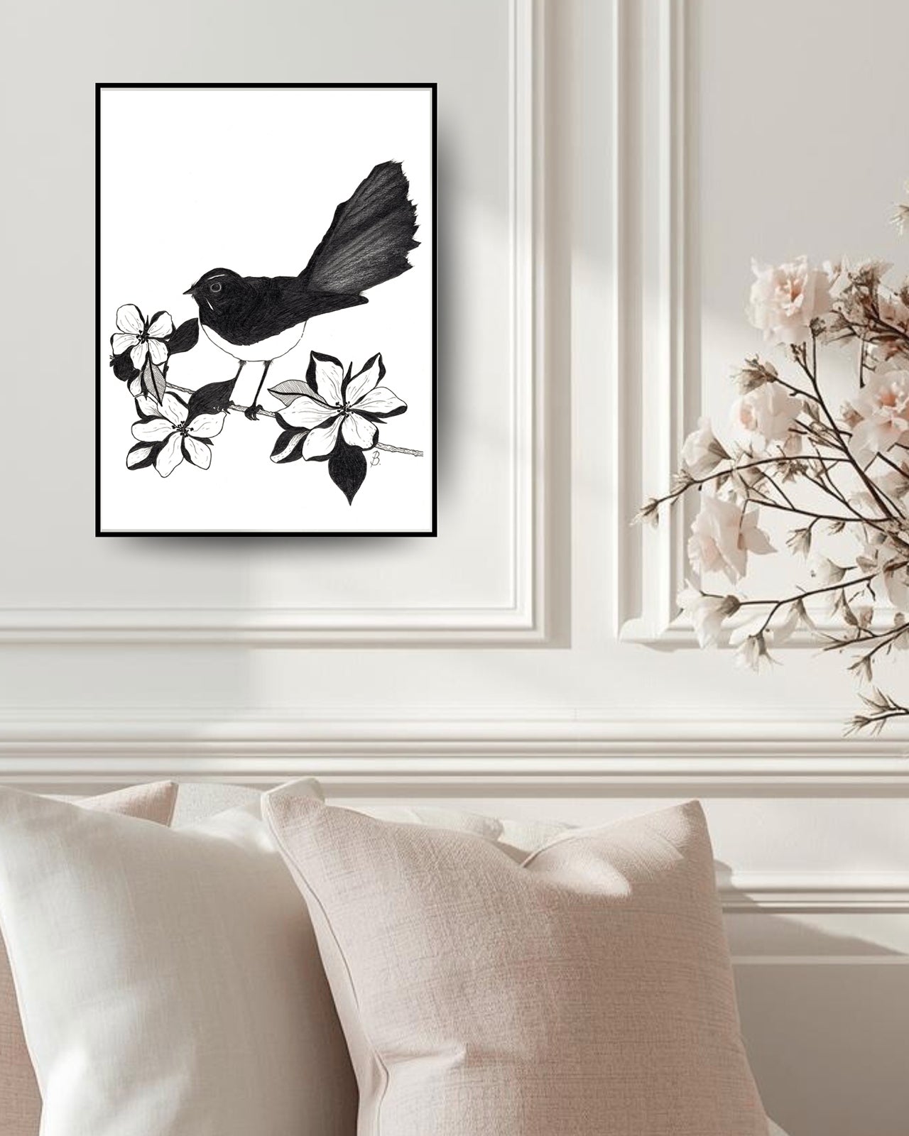'Willie Wagtail and Magnolias' original Graphite Pencil Drawing by Bridget Bradley, seen in black frame without mat hanging on white wall panel above cushions. Learn more about this fine art drawing