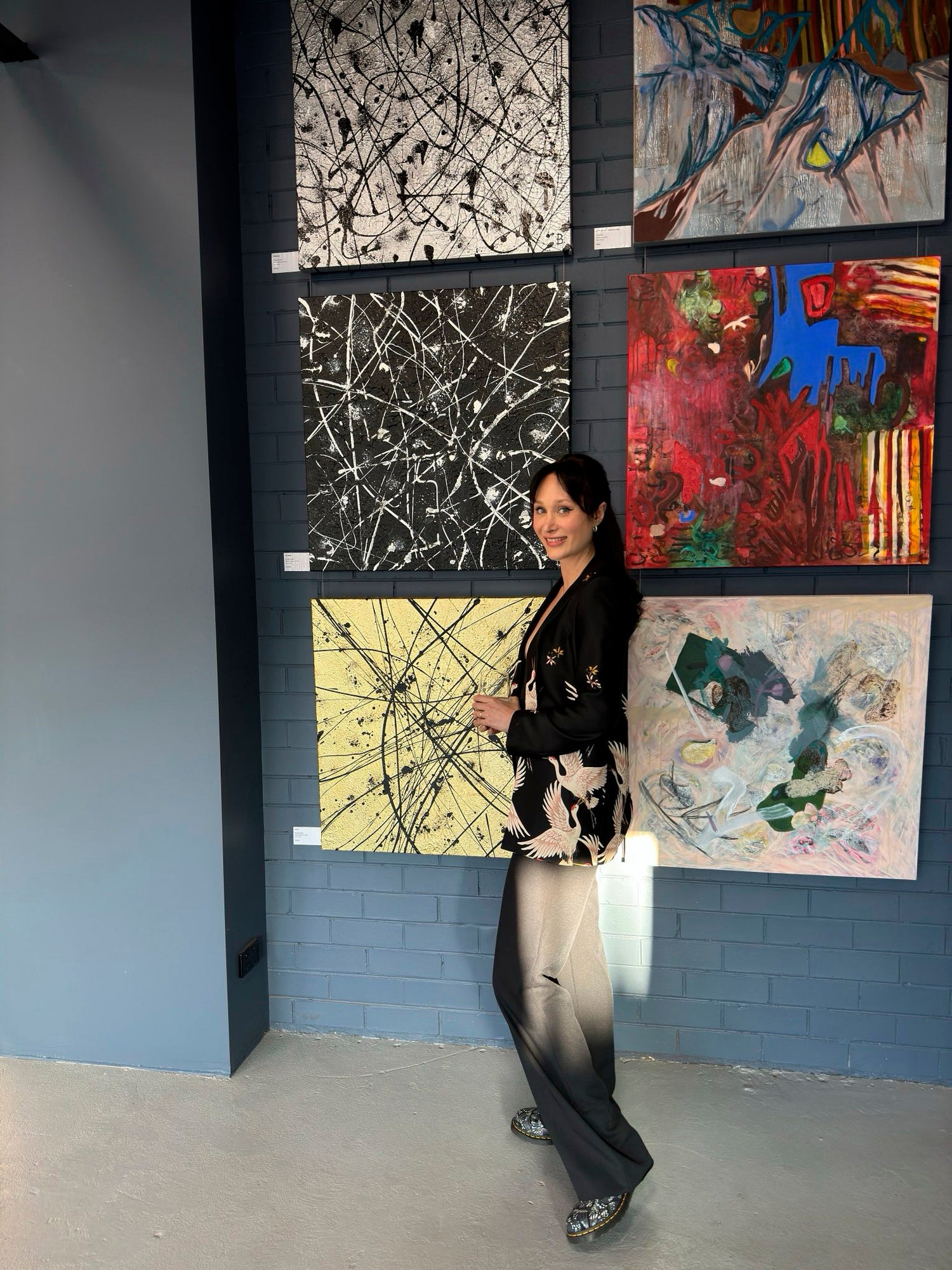 Bridget Bradley, abstract artist on opening night at the Salon exhibition Melbourne Art Lovers Australia Gallery standing by her three exhibited artworks, from top left, Platinum, Graphite and Gold.