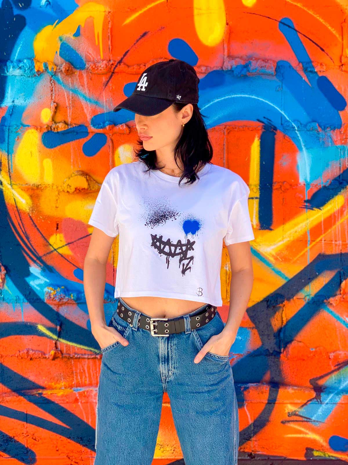 Bridget Models her Smile Crop Top Tee Print Design against a brightly painted wall. Shop B-Contemporary-Streetwear