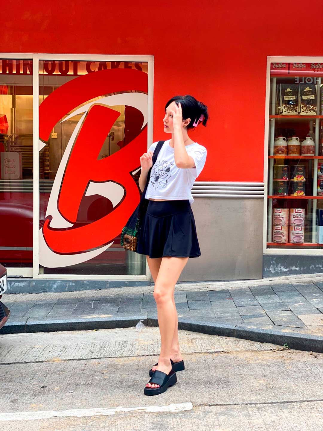 Bridget Wearing The Eva Crop Top Tee with black mini skirt, standing on street