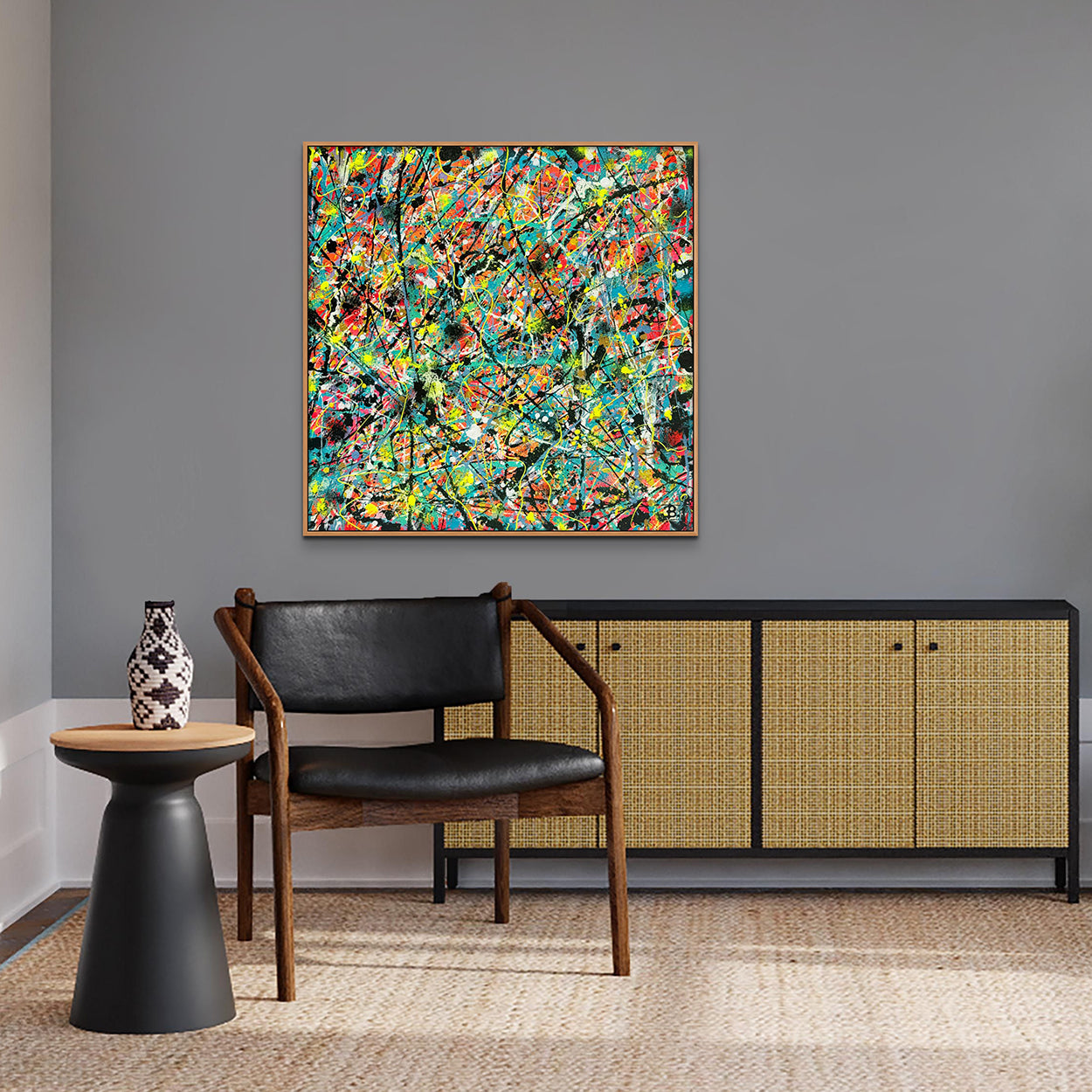 'Labyrinth' original abstract by Bridget Bradley. Square canvas in mulitple colours and neon hanging above a rattan and black console beside black leather chair and table. Learn more about this unique abstract art.