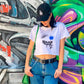 Printed Smile Crop Top Tee Front. Model & Designer Bridget wear her design with blue jeans and black cap. Shop B-Contemporary-Streetwear