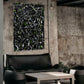 'Space Rock' original abstract painting on canvas with black background, white and neon yellow marks seen hanging above a black sofa. Painting by Bridget Bradley, Abstract Artist, Australia