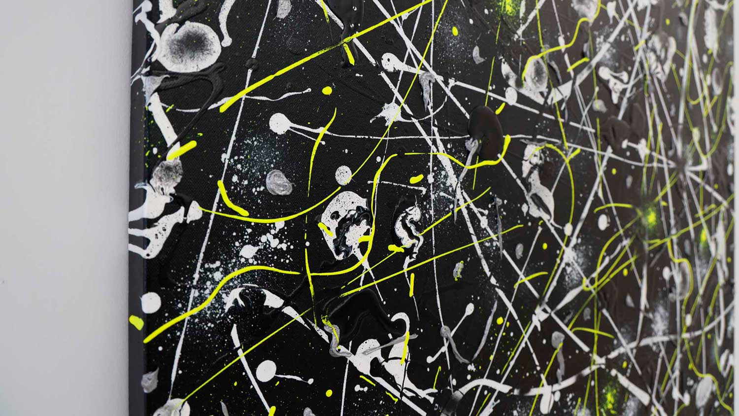 'Space Rock' , large, contemporary abstract hand-painted by Bridget Bradley,seen from the side view of the canvas. Black background, white, grey and neon yellow marks. Learn more!