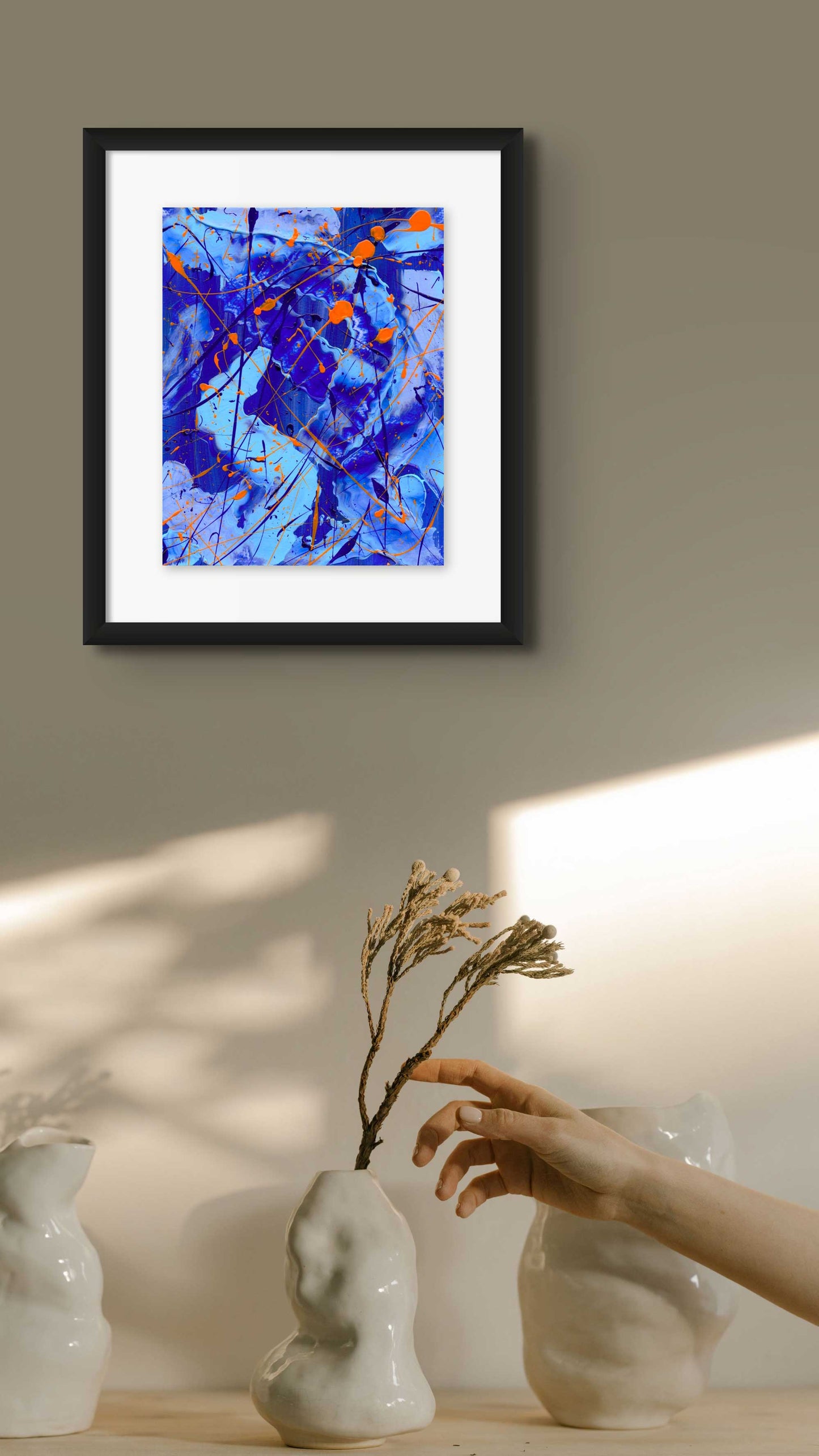 Blue I, original abstract painting seen in black frame hanging on wall with vase. Abstract by Bridget Bradley