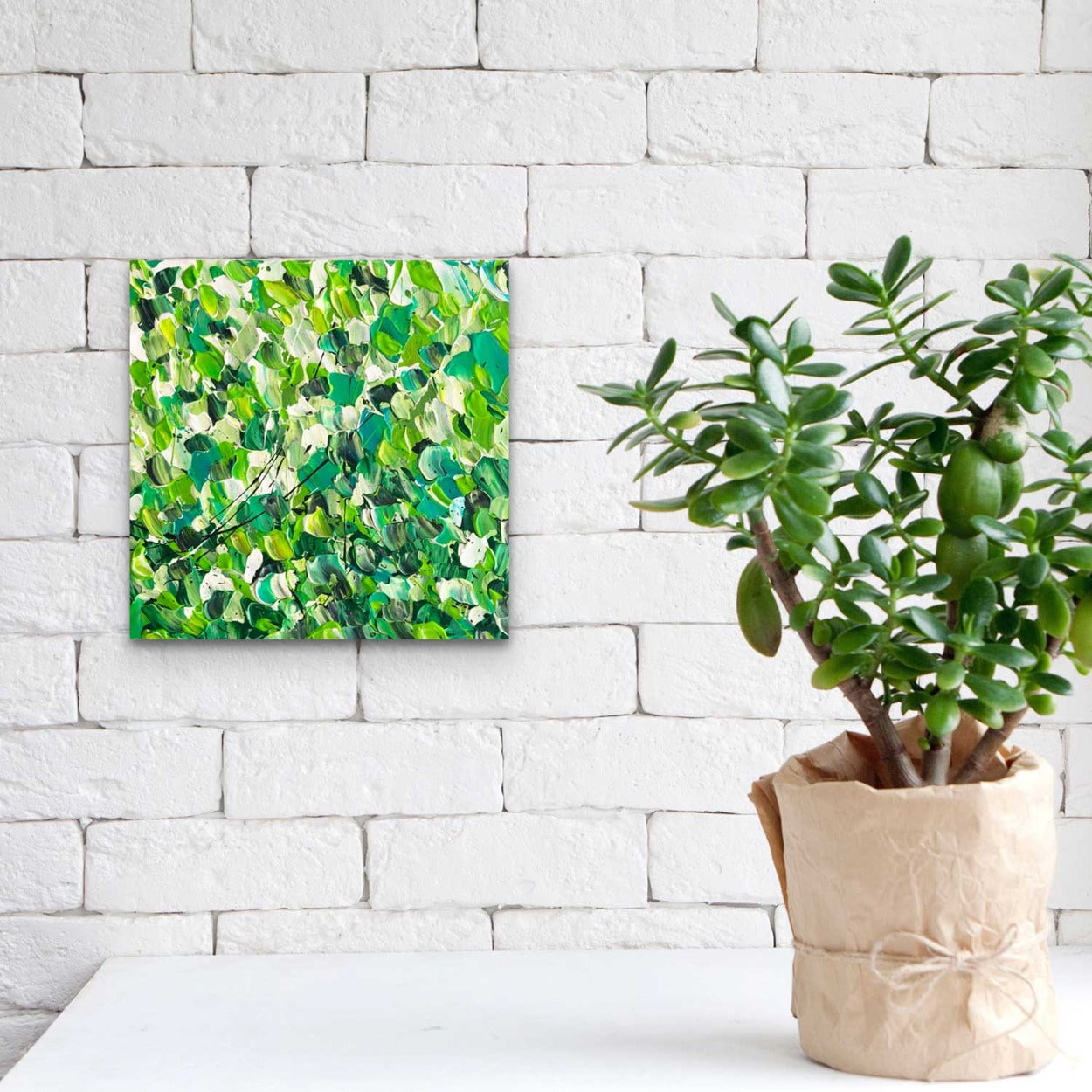 Fields of Green original , textured abstract canvas wall art against white brick wall near pot plant. Painted by Bridget Bradley