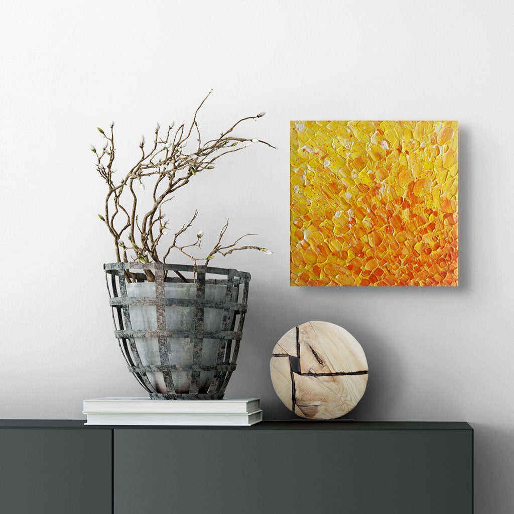 'In the Heart of the Sun' original abstract painting on canvas in bold, warm yellow, orange and gold colour with heavy texture seen hanging in situ above dark console with ornaments. Artwork created by Bridget Bradley, Abstract Artist , Australia