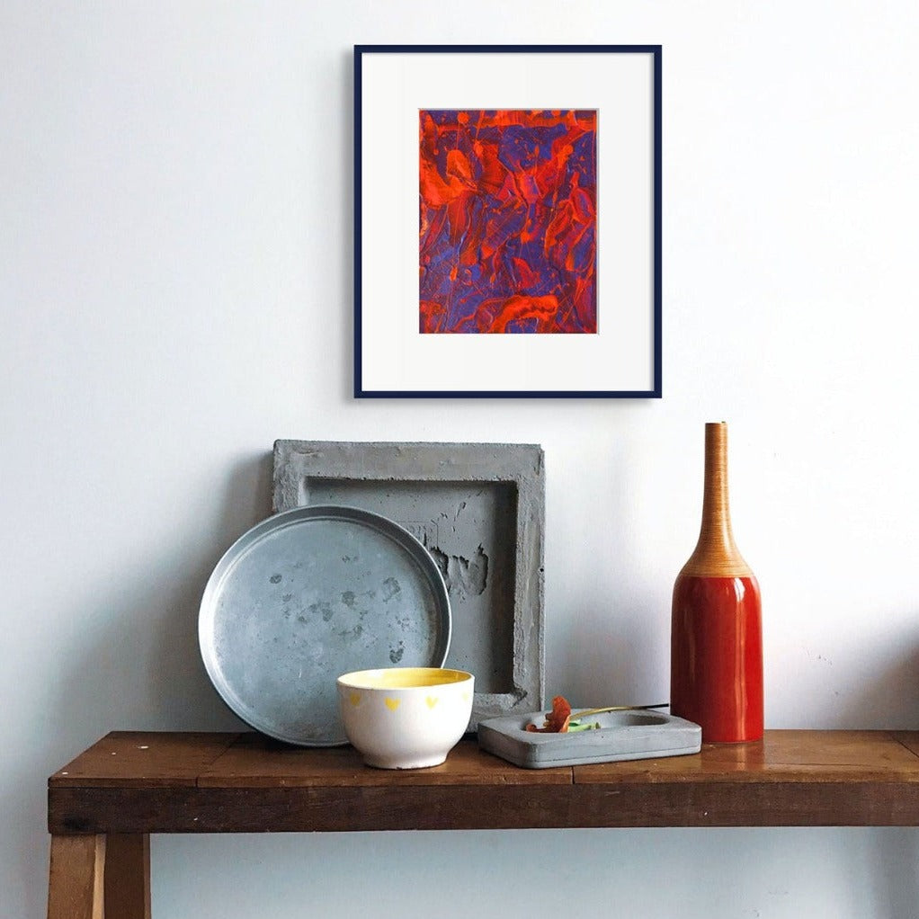 Little Luxuries VI, original abstract painting by Bridget Bradley seen hanging on a white wall above a wooden table with blue pottery plates and a red bottle
