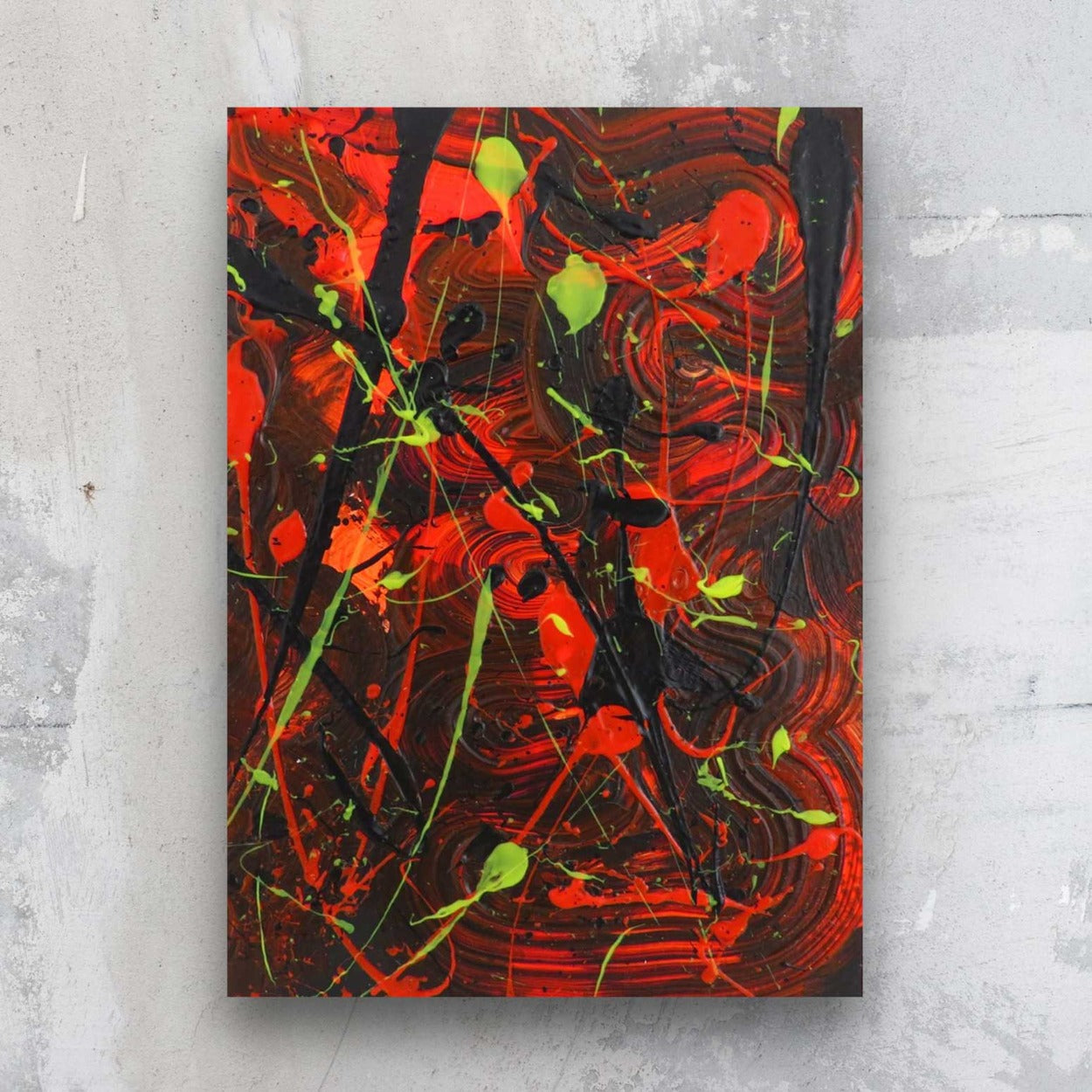 Little Luxuries XIV, original abstract art on paper by Bridget Bradley. Colour palette, dark background  with swirls of neons red ornages and neon yellow and black marks, seen against a stone wall in situ