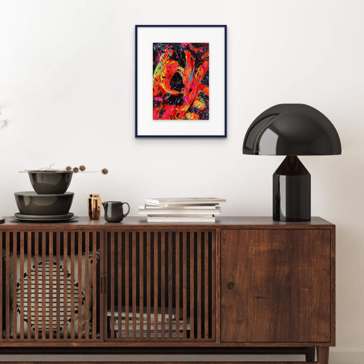 Little Luxuries XV, bold abstract painting seen framed in balck with white mat hanging above a wooden cabinet with black lamp. Artwork created by Brigdet Bradley, abstract expressionism artist