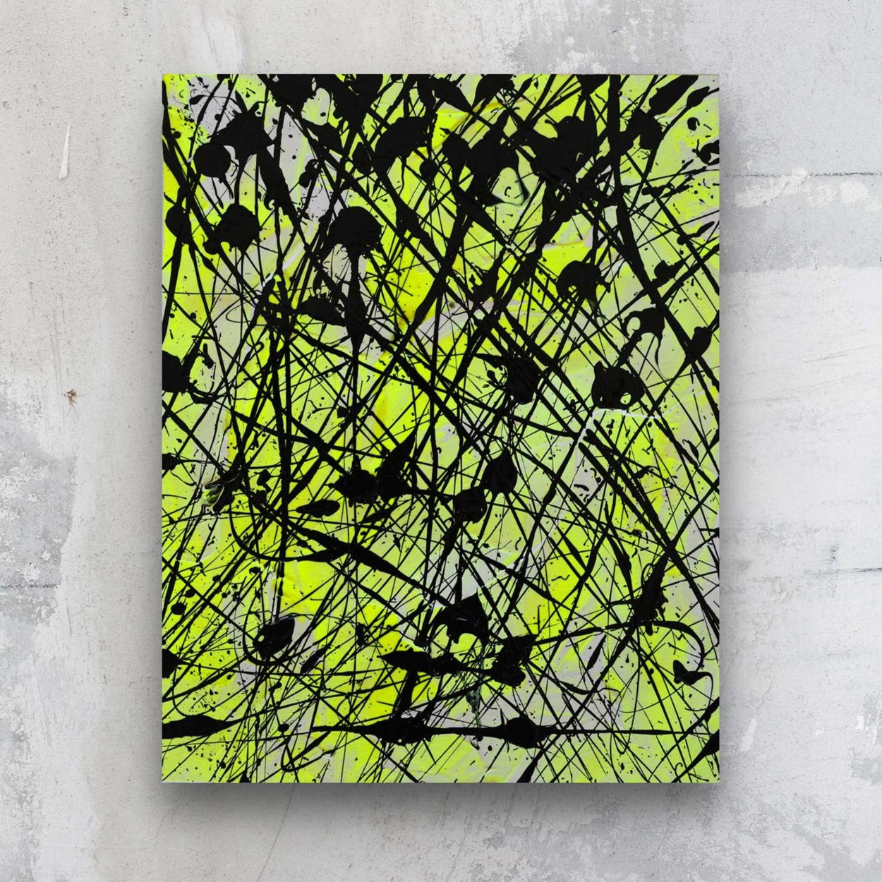 Neon I, original abstract art on paper in neon yellow and black, painted by Brigdet Bradley. Seen hanging against a stone wall.