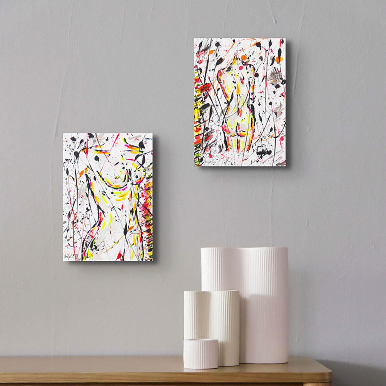 From left, Nude I original abstract painting of female figure seen hanging on wall paired with Nude II above wooden table with white accessories.  Abstract art by Bridget Bradley