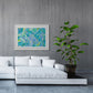 'Ocean' Large abstract paper art print framed in white with white mat. Seen in situ above white leather sofa and with pot plant. After the original artwork by Bridget Bradley