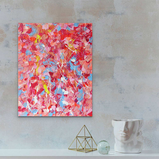 'Pink Lake', textured abstract painting, pinks, nudes, reds, blue, yellow and white palette. Seen in situ against concrete wall with modern decor.